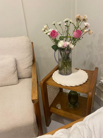 "Rattan side table with lamp and decor styled on top"